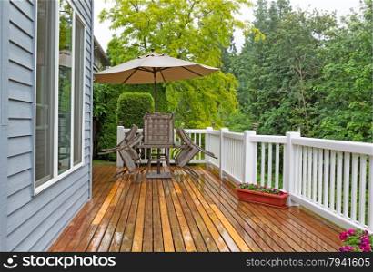 Horizontal photo of outdoor patio furniture put away due to poor weather. Photo taken during heavy rain on cedar wood deck.