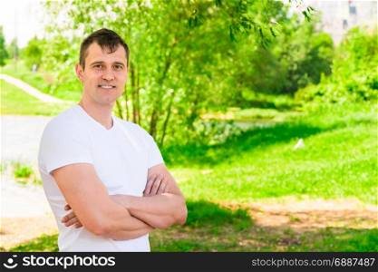 Horizontal portrait of a handsome man in a white T-shirt in the park