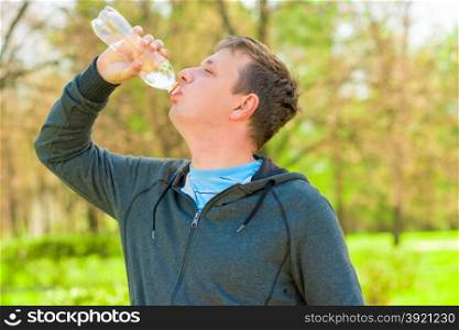 Horizontal portrait of a man drinking water from a small bottle
