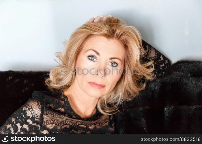 Horizontal portrait of adult blond woman with makeup on black fur