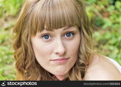 Horizontal portrait of young woman with big bulging blue eyes on summer background