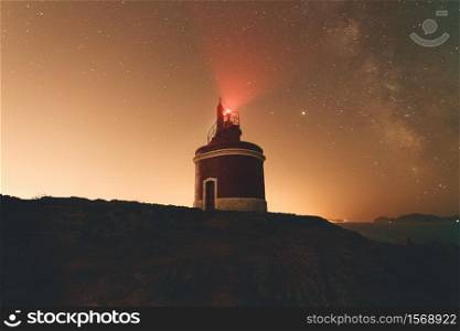 Horizontal shot of a lighthouse during the night with the sky with a lot of stars
