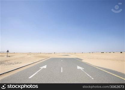 Horizontal shot of an empty road in the desert with large copy space in the blue sky. Road in the desert