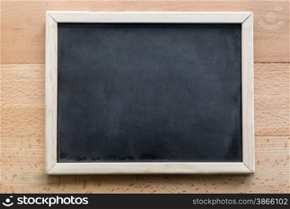 Horizontal shot of empty blackboard lying on wooden desk