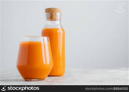 Horizontal shot of fresh carrot juice in glass containers, rich with vitamins, isolated on white wall with empty space. Vegetable drink