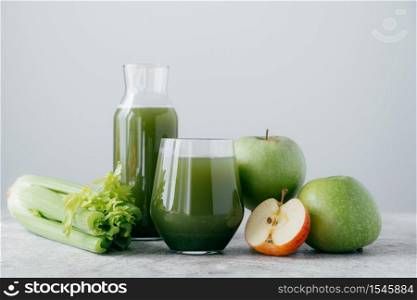 Horizontal shot of freshly blended apples and cerely for your healthy eating. Vegetarian green drink in glasses. Detox beverage, fruits and vegetable around