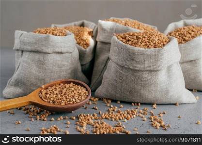Horizontal shot of roasted buckwheat in sacks and spoon. Gluten free grains. Harvested uncooked cereals. Natural vegan food concept