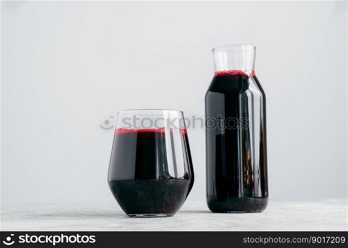 Horizontal shot of two glass containers full of fresh beetroot juice, isolated on white background. Vitaminized drink made of vegetables
