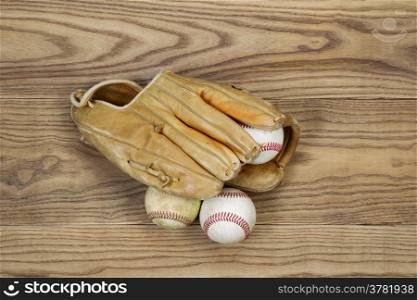 Horizontal top view photo of old baseball glove and balls on top of faded wood&#xA;