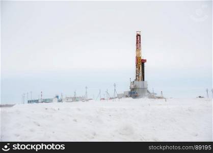 Horizontal view of a derrick drilling and pipeline valve in severe winter. Extraction of oil. Petroleum concept.. Pump jack and oil rig situated in forest.