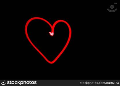horizontal view of a red heart outline light painting in black night sky
