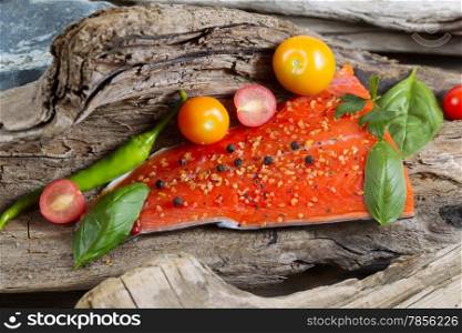 Horizontal view of raw salmon fillet, skin side down, with seasoning inside of drift wood