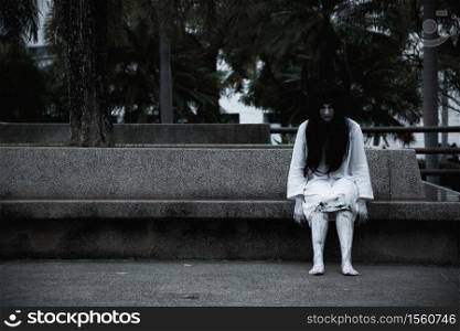 Horror woman ghost creepy sitting under the tree on garden, halloween day concept