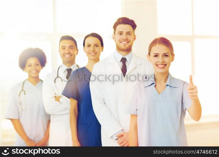 hospital, profession, gesture, people and medicine concept - group of happy doctors showing thumbs up at hospital