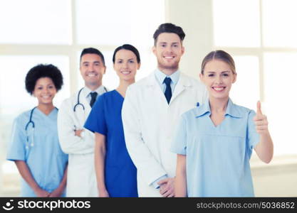 hospital, profession, gesture, people and medicine concept - group of happy doctors showing thumbs up at hospital. happy doctors showing thumbs up at hospital