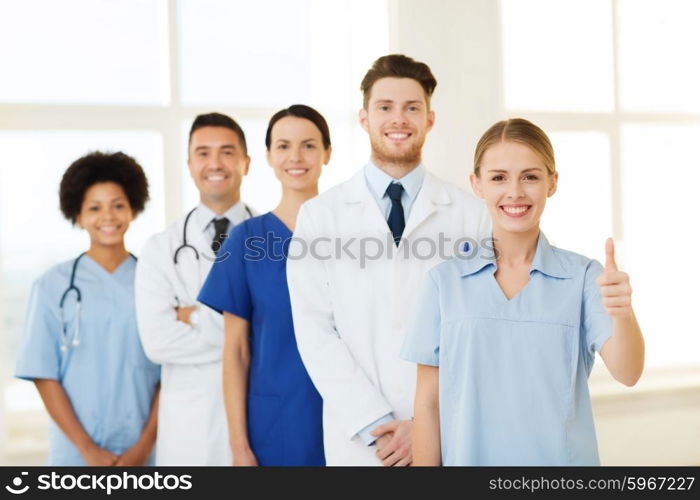 hospital, profession, gesture, people and medicine concept - group of happy doctors showing thumbs up at hospital