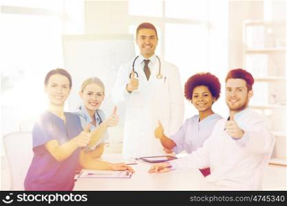 hospital, profession, medical education, people and medicine concept - group of happy doctors meeting on presentation or conference at hospital and showing thumbs up gesture