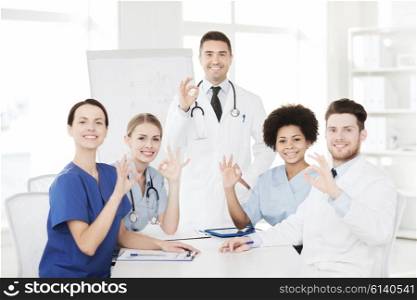 hospital, profession, medical education, people and medicine concept - group of happy doctors meeting on presentation or conference at hospital and showing ok hand sign