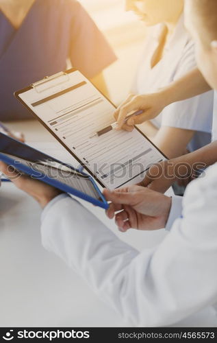 hospital, profession, people and medicine concept - close up of doctors with clipboard meeting and discussing medical report at medical office