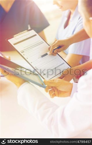 hospital, profession, people and medicine concept - close up of doctors with clipboard meeting and discussing medical report at medical office