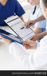 hospital, profession, people and medicine concept - close up of doctors with clipboard meeting and discussing medical report at medical office