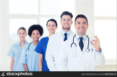 hospital, profession, people and medicine concept - group of happy doctors at hospital showing ok hand sign. group of happy doctors at hospital