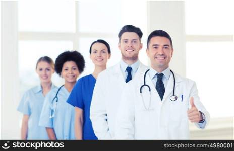 hospital, profession, people and medicine concept - group of happy doctors at hospital showing thumbs up gesture. group of happy doctors at hospital