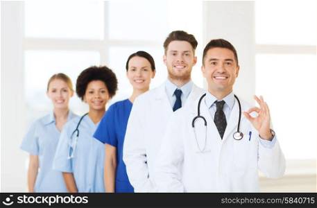 hospital, profession, people and medicine concept - group of happy doctors at hospital showing ok hand sign
