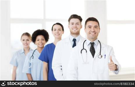 hospital, profession, people and medicine concept - group of happy doctors at hospital showing thumbs up gesture
