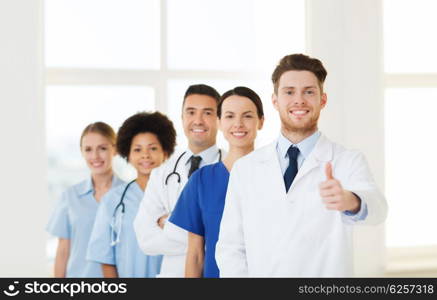 hospital, profession, people and medicine concept - group of happy doctors at hospital showing thumbs up gesture