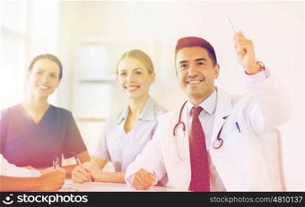 hospital, profession, people and medicine concept - group of happy doctors meeting and asking questions on conference at hospital