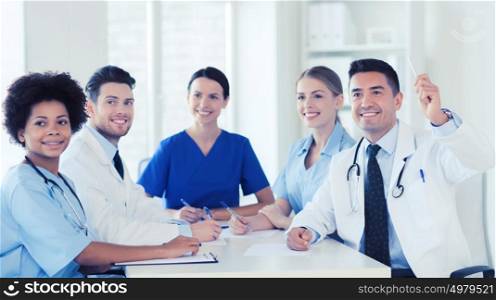 hospital, profession, people and medicine concept - group of happy doctors meeting and asking questions on conference at hospital. group of happy doctors on conference at hospital