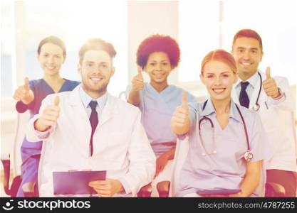 hospital, profession, people and medicine concept - group of happy doctors on seminar in lecture hall at hospital showing thumbs up gesture