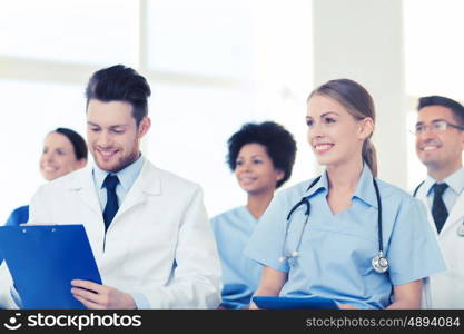 hospital, profession, people and medicine concept - group of happy doctors on seminar in lecture hall at hospital