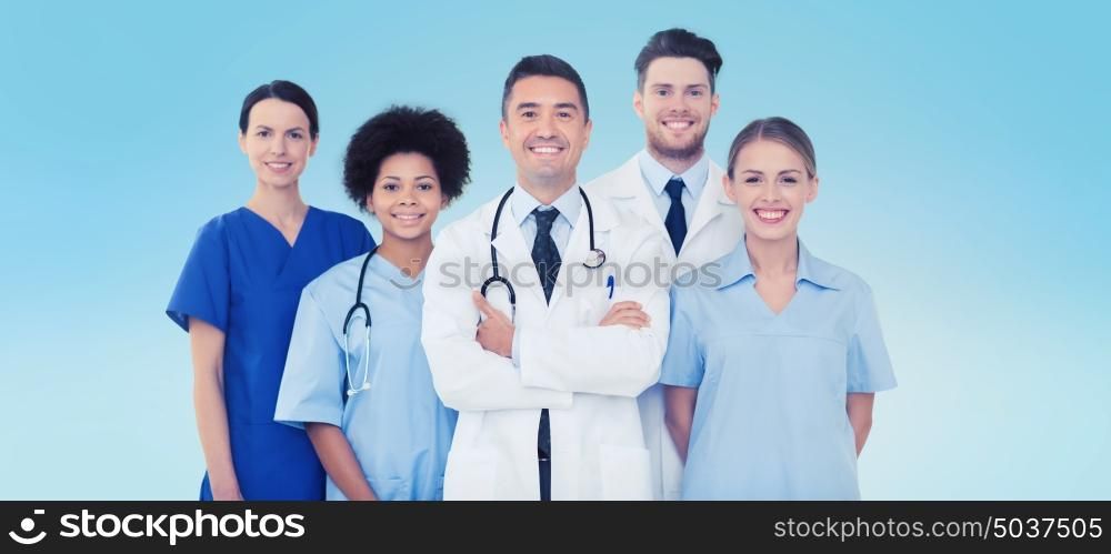 hospital, profession, people and medicine concept - group of happy doctors over blue background. group of happy doctors over blue background
