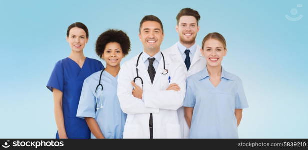 hospital, profession, people and medicine concept - group of happy doctors over blue background