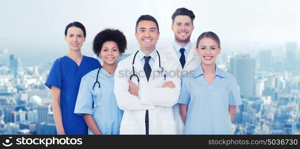 hospital, profession, people and medicine concept - group of happy doctors over city background. group of happy doctors over blue background
