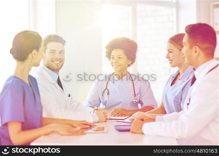 hospital, profession, people and medicine concept - group of happy doctors with tablet pc computers meeting at medical office
