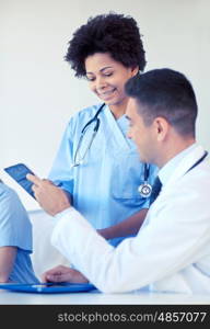 hospital, profession, people and medicine concept - group of happy doctors with tablet pc computers meeting at medical office