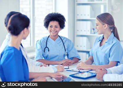 hospital, profession, people and medicine concept - group of happy doctors with tablet pc computers meeting at medical office. group of happy doctors meeting at hospital office