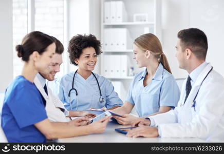 hospital, profession, people and medicine concept - group of happy doctors with tablet pc computers meeting at medical office