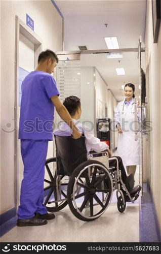 Hospital Staff Pushing Patient In Wheelchair
