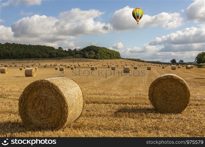 Hot air balloon drifting over farmland at harvest time - North Yorkshire in the United Kingdom.