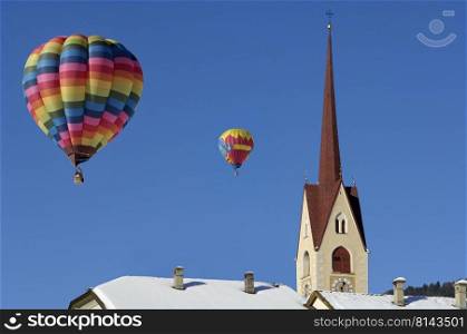 Hot air balloons in the sky above a church