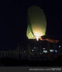 Hot air lantern taking off in dark sky, vertical image