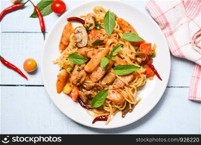 Hot and spicy Spaghetti Pasta tomato chilli and basil leaves top view / Traditional delicious Italian food spaghetti sausage on plate on the dining table
