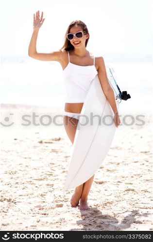 Hot beach model waving and holding surfboard at the beach