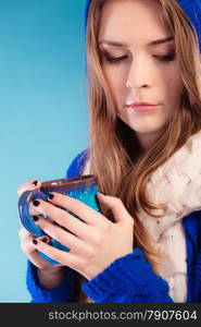 Hot beverage. Closeup teen girl holding blue mug with drink tea or coffee. Woman warming herself