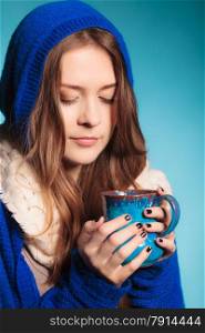 Hot beverage. Closeup teen girl holding blue mug with drink tea or coffee. Woman warming herself