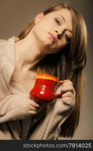 Hot beverage. Sleepy girl holding cup mug of drink tea or coffee. Woman in warm sweater warming herself